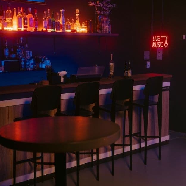 Standing bar set with a neon Live Music sign and purple mood lighting
